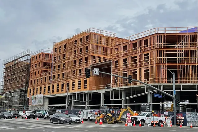 A building under construction with cars parked in front of it.